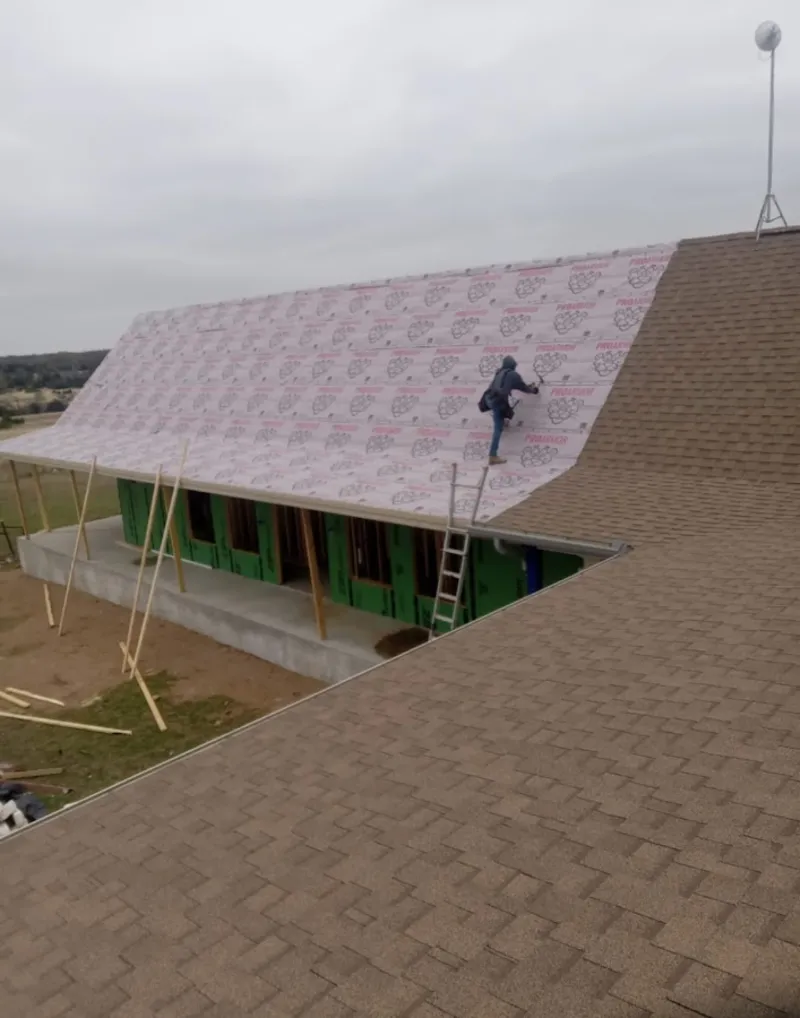 Worker preparing underlayment for a metal roof installation in Bacliff